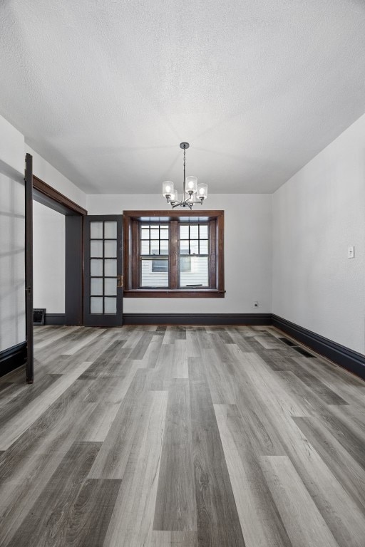 1818 Park Ave SE, Cedar Rapids, IA 52403 - unfurnished room with a textured ceiling, a chandelier, and wood finished floors