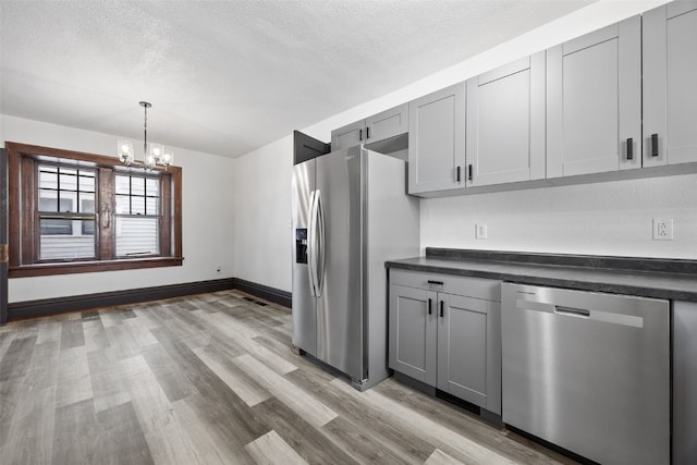 1818 Park Ave SE, Cedar Rapids, IA 52403 - kitchen with appliances with stainless steel finishes, gray cabinets, a chandelier, dark countertops, and a textured ceiling