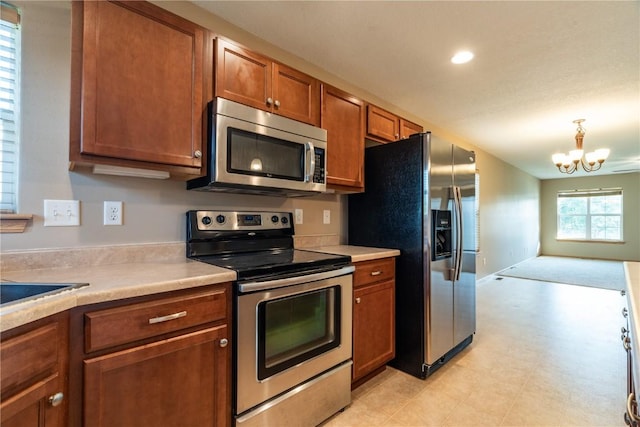 6045 Ridgewood Meadows Ln NE, Cedar Rapids, IA 52411 - kitchen featuring appliances with stainless steel finishes, light countertops, brown cabinets, a chandelier, and open floor plan
