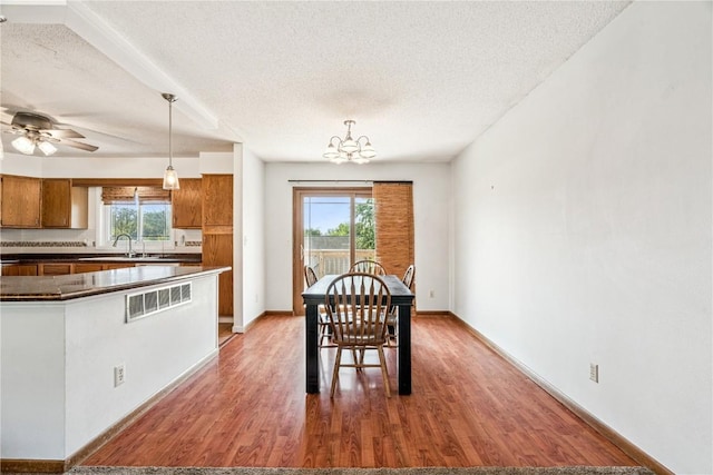 4185 Richland Dr, Cedar Rapids, IA 52405 - dining room featuring a textured ceiling, light wood finished floors, a chandelier, and ceiling fan
