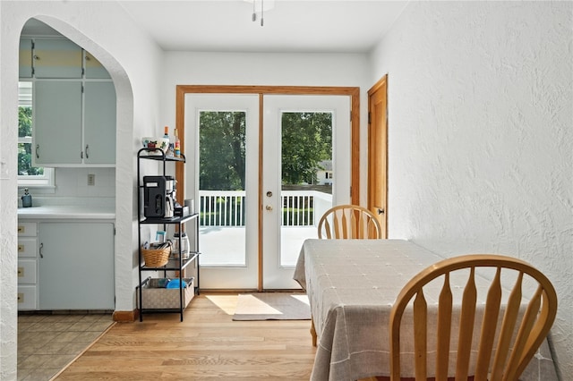 1039 27th St NE, Cedar Rapids, IA 52214 - dining room featuring a textured wall, arched walkways, light wood-style floors, and french doors