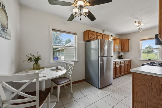 2226 Chandler SW, Cedar Rapids, IA 52404 - kitchen featuring freestanding refrigerator, brown cabinetry, light countertops, ceiling fan, and light tile patterned floors