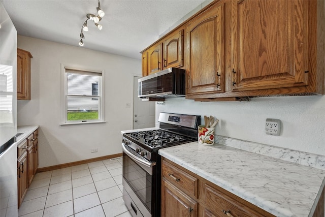 2226 Chandler SW, Cedar Rapids, IA 52404 - kitchen with stainless steel appliances, brown cabinetry, light tile patterned floors, and rail lighting