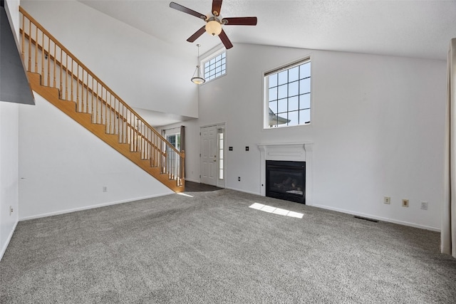 1167 74th St NE, Cedar Rapids, IA 52402 - unfurnished living room featuring stairs, a ceiling fan, carpet floors, a glass covered fireplace, and high vaulted ceiling