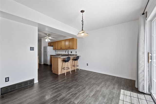 1167 74th St NE, Cedar Rapids, IA 52402 - kitchen with a kitchen bar, dark wood-style floors, a peninsula, and ceiling fan