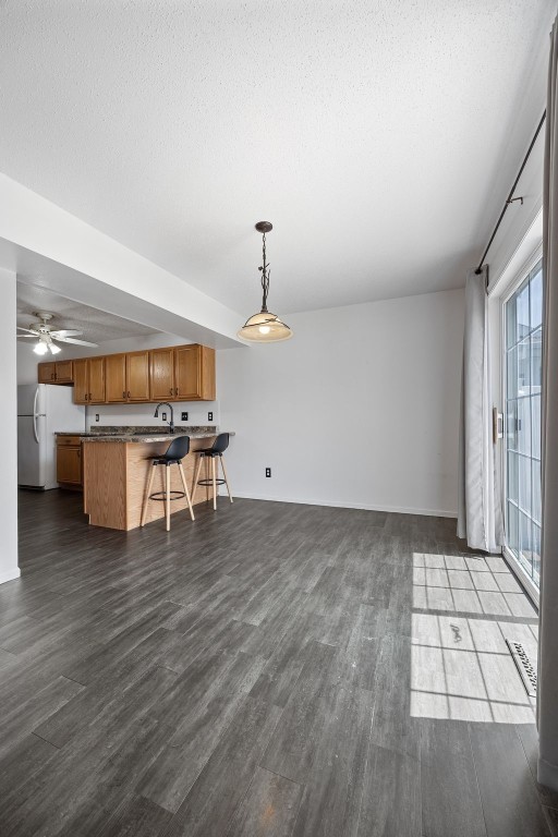 1167 74th St NE, Cedar Rapids, IA 52402 - kitchen featuring open floor plan, a breakfast bar area, brown cabinets, a peninsula, and dark wood finished floors