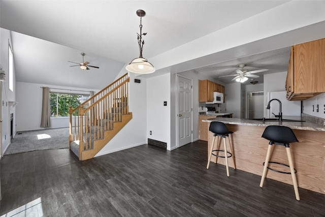 1167 74th St NE, Cedar Rapids, IA 52402 - kitchen featuring ceiling fan, a peninsula, dark wood-style floors, vaulted ceiling, and pendant lighting