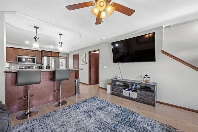 3221 English Cove Ln, Marion, IA 52302 - kitchen with a breakfast bar area, stainless steel appliances, light wood finished floors, decorative light fixtures, and light countertops