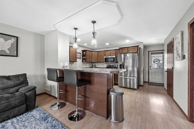 3221 English Cove Ln, Marion, IA 52302 - kitchen featuring stainless steel appliances, a peninsula, light wood-style flooring, a breakfast bar area, and open floor plan