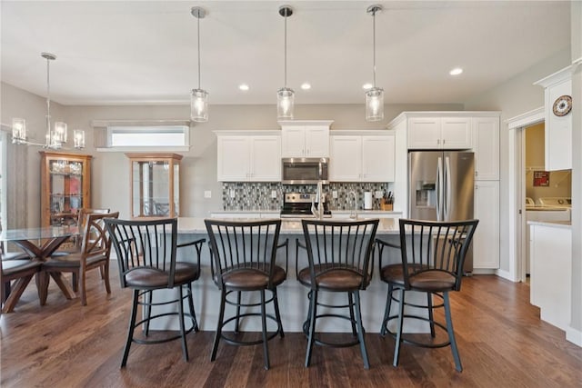 1627 Settlers Dr, Marion, IA 52302 - kitchen featuring stainless steel appliances, white cabinets, light countertops, decorative backsplash, and a center island with sink