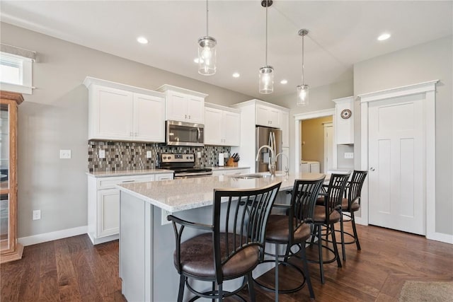 1627 Settlers Dr, Marion, IA 52302 - kitchen with appliances with stainless steel finishes, a kitchen island with sink, decorative backsplash, white cabinets, and recessed lighting