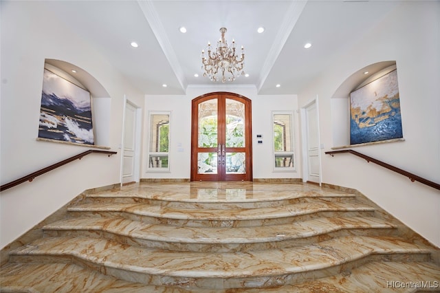 foyer with french doors, a notable chandelier, and crown molding