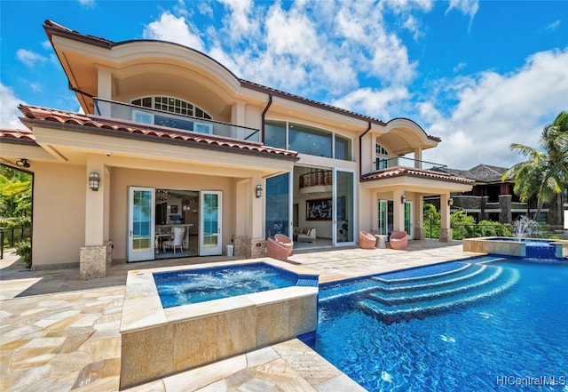 rear view of property featuring a balcony, a swimming pool with hot tub, pool water feature, and a patio