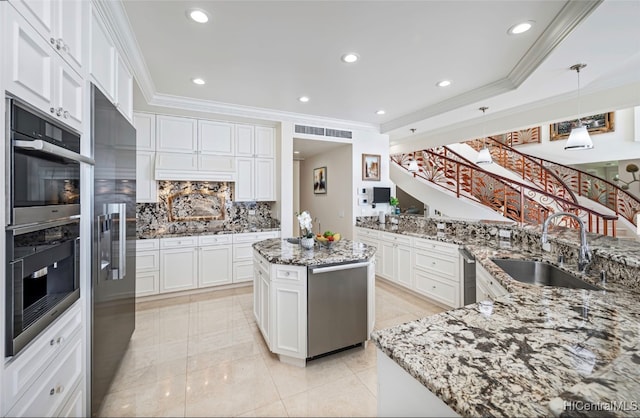 kitchen with tasteful backsplash, sink, a kitchen island, decorative light fixtures, and white cabinets