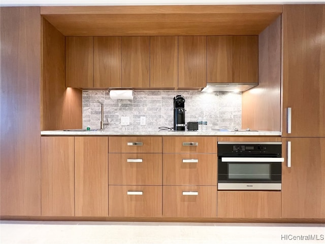 kitchen featuring decorative backsplash, sink, and stainless steel oven