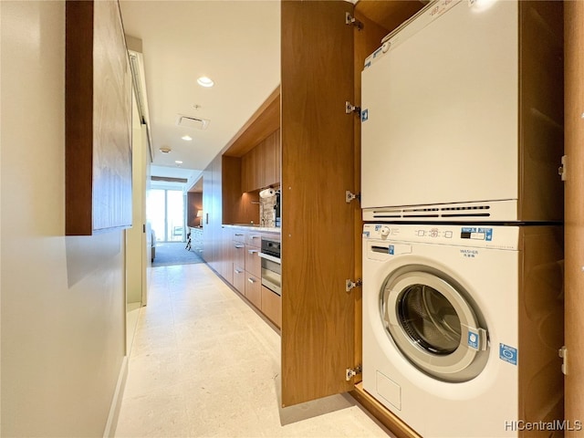 clothes washing area with stacked washer / dryer