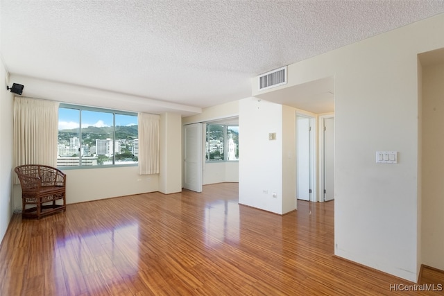 spare room with a textured ceiling and hardwood / wood-style floors