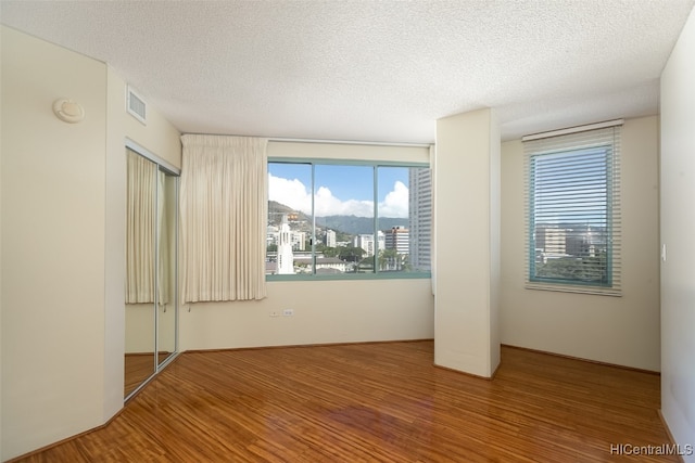 empty room with a textured ceiling and hardwood / wood-style floors