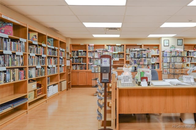 home office with a drop ceiling and light wood-type flooring