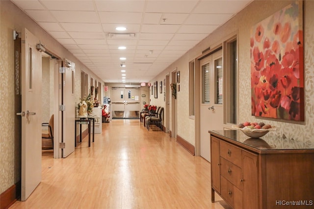 hallway with a drop ceiling and light wood-type flooring