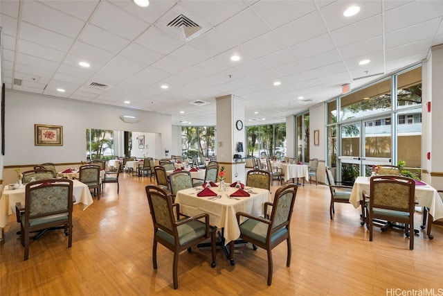 dining space featuring a drop ceiling, light hardwood / wood-style flooring, and a healthy amount of sunlight