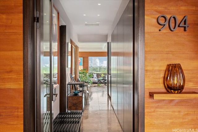 hall with wood walls and light tile patterned floors