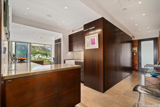 kitchen featuring dark brown cabinetry, kitchen peninsula, light tile patterned floors, and wood walls