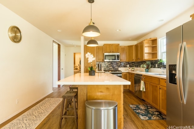 kitchen featuring a breakfast bar, stainless steel appliances, dark wood-type flooring, pendant lighting, and a center island