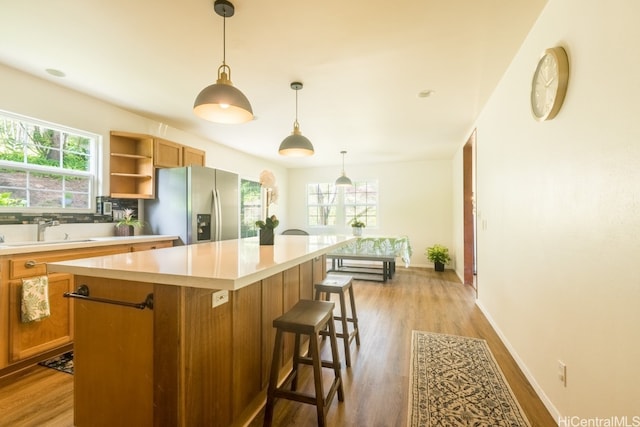 kitchen featuring a healthy amount of sunlight, sink, a kitchen island, and stainless steel fridge with ice dispenser