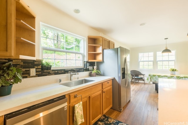 kitchen with light hardwood / wood-style flooring, stainless steel appliances, decorative light fixtures, and a wealth of natural light