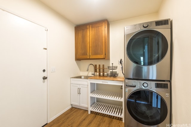 laundry room with light hardwood / wood-style flooring, stacked washer / dryer, cabinets, and sink