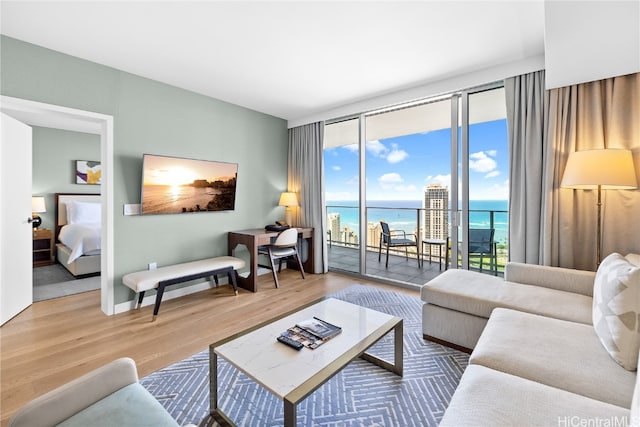 living room with hardwood / wood-style floors, a water view, and expansive windows