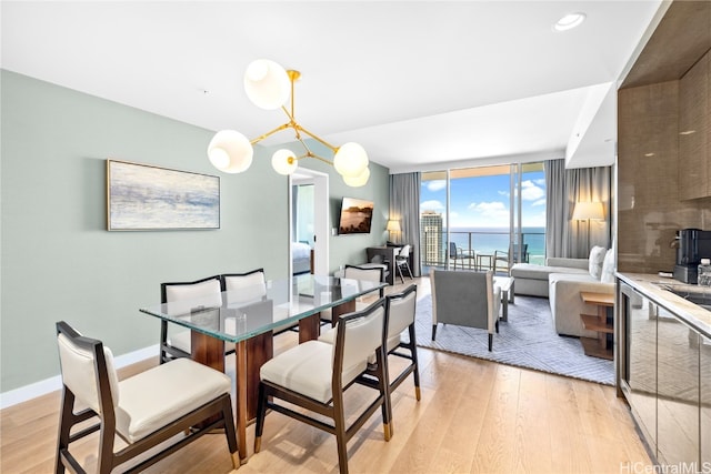 dining area with expansive windows, light hardwood / wood-style flooring, and an inviting chandelier