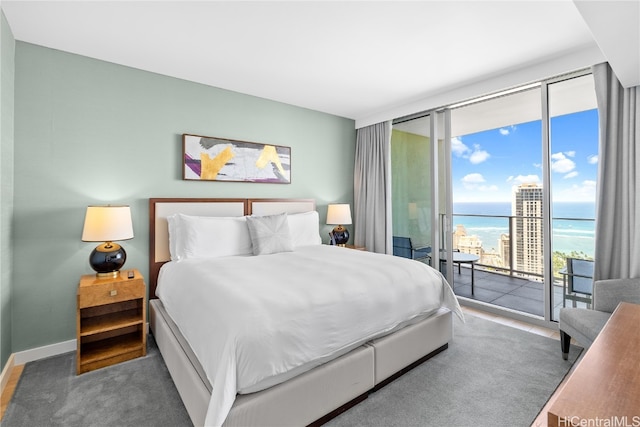 bedroom with a wall of windows, a water view, and access to outside