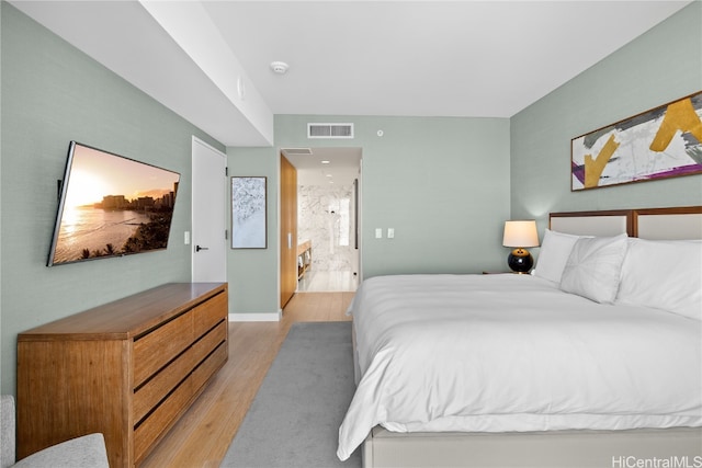 bedroom featuring connected bathroom and light hardwood / wood-style floors