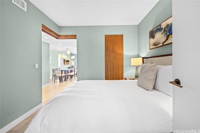 bedroom featuring an inviting chandelier and light hardwood / wood-style floors