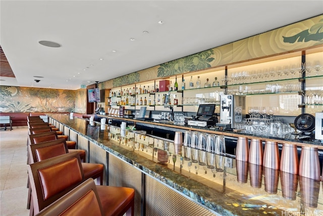 bar featuring dark stone counters, pendant lighting, and light tile patterned floors