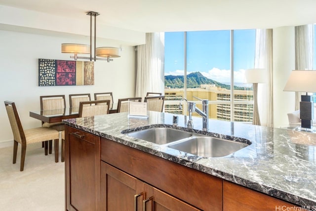 kitchen featuring a mountain view, light carpet, dark stone countertops, sink, and pendant lighting