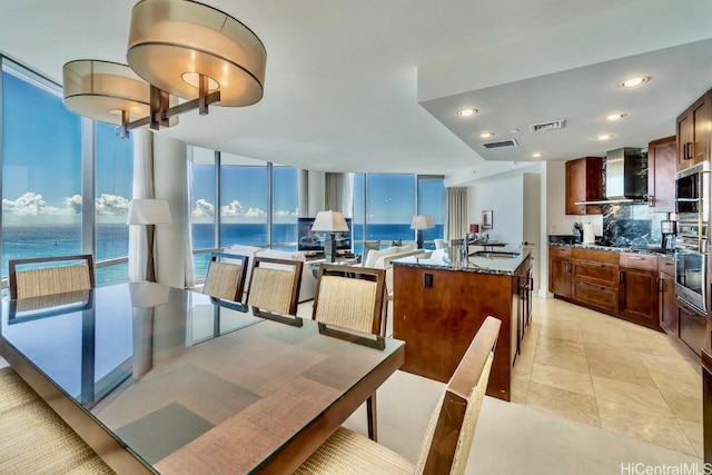 tiled dining space featuring a water view, expansive windows, and sink