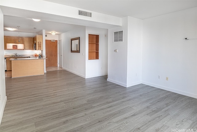 unfurnished living room featuring sink and light hardwood / wood-style flooring