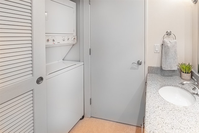 washroom with stacked washer / drying machine and sink