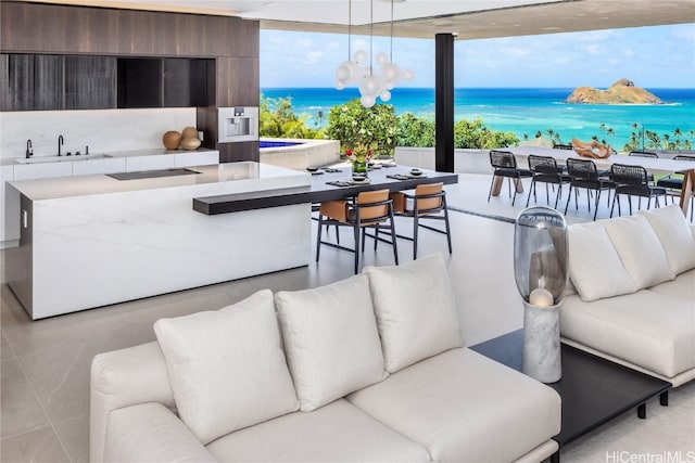 living room with a water view, sink, an inviting chandelier, and floor to ceiling windows