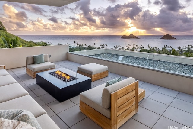 patio terrace at dusk with a water view and an outdoor living space with a fire pit