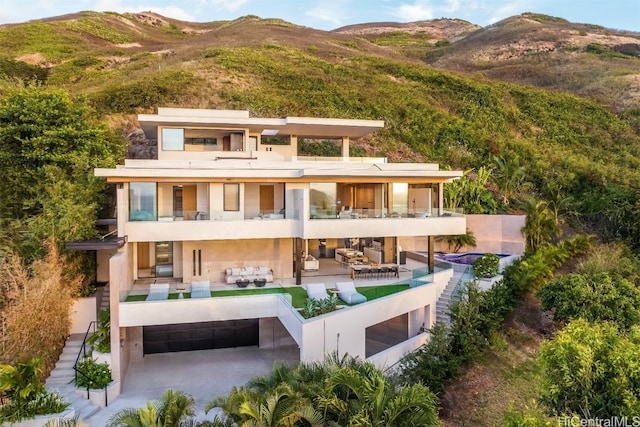 rear view of house with an outdoor living space, a balcony, a mountain view, and a patio area