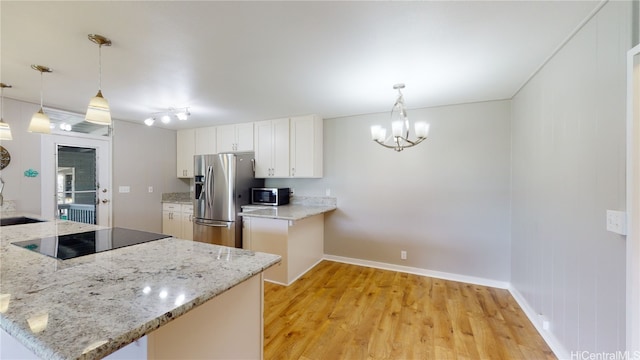 kitchen with appliances with stainless steel finishes, decorative light fixtures, kitchen peninsula, and white cabinets