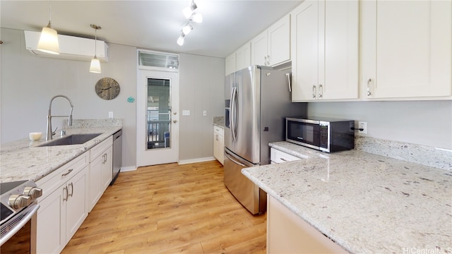 kitchen with sink, decorative light fixtures, appliances with stainless steel finishes, light stone countertops, and white cabinets