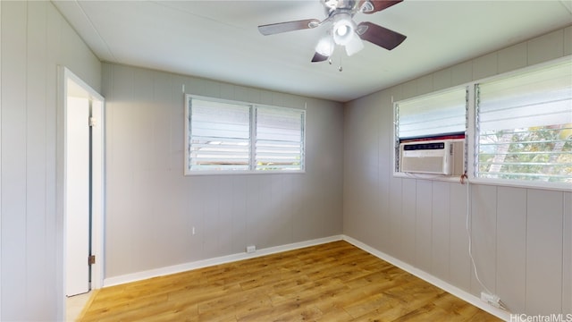 empty room featuring cooling unit, ceiling fan, and light hardwood / wood-style floors