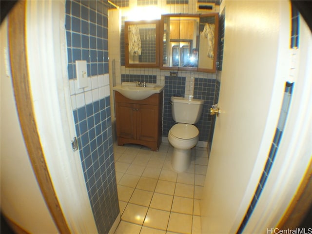 bathroom with vanity, toilet, tile patterned floors, and tile walls