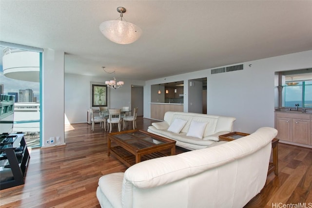 living room with visible vents, an inviting chandelier, and wood finished floors