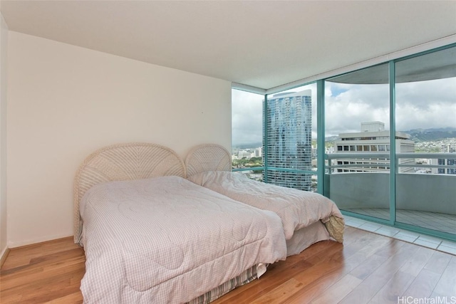 bedroom with expansive windows and wood finished floors